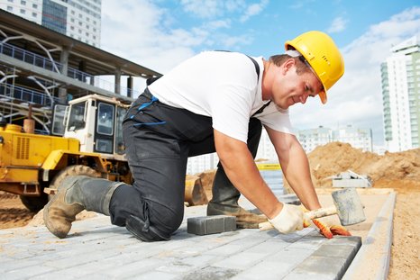 Symbolic image of a worker at a construction site laying concrete blocks